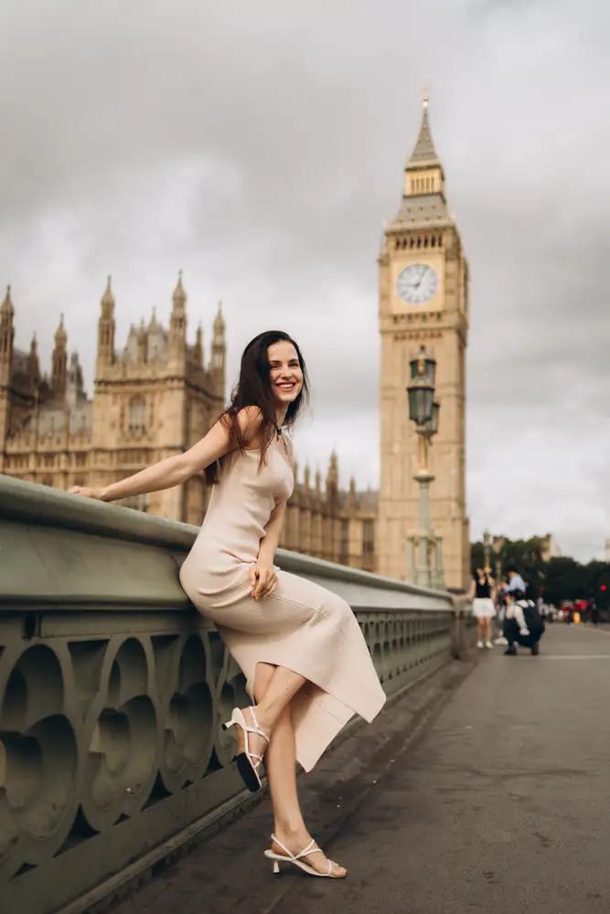 Smiling woman leaning on the Westminster Bridge railing by Big Ben