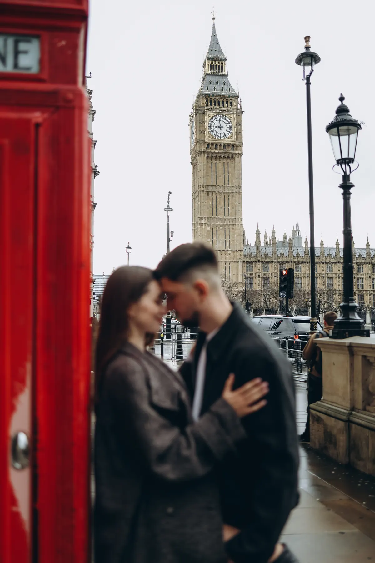 Couple in soft focus by a red phone box with Big Ben sharp in the background