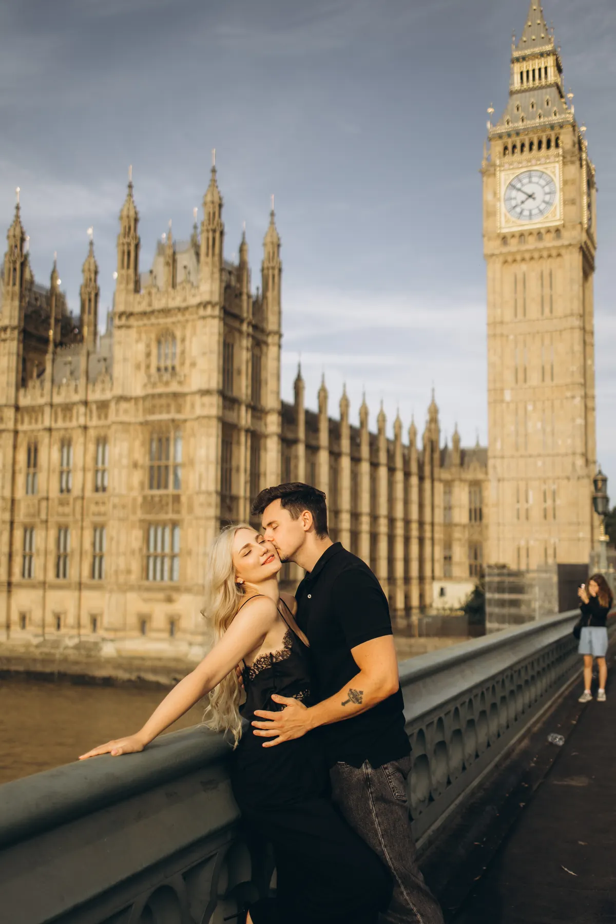 Man kissing his partner on the cheek on Westminster Bridge by the Houses of Parliament