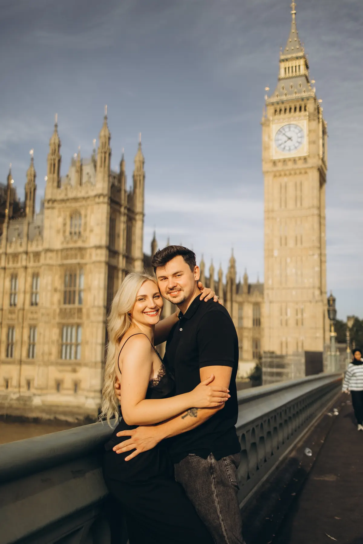 Smiling couple hugging on Westminster Bridge below Big Ben