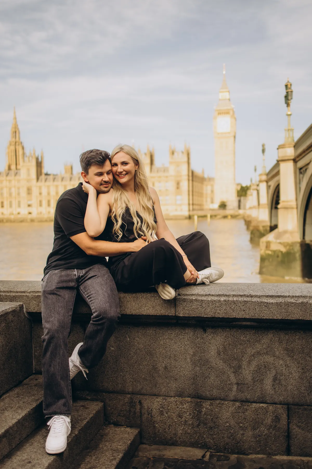 Couple sitting on the river wall opposite the Houses of Parliament and Big Ben