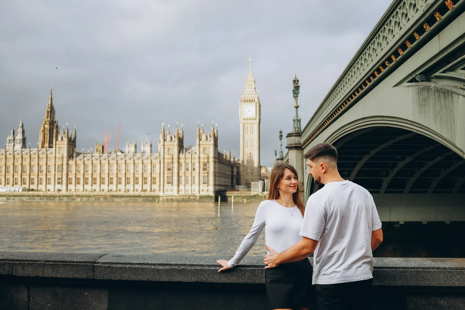 Couple by the river wall on the South Bank facing the Palace of Westminster