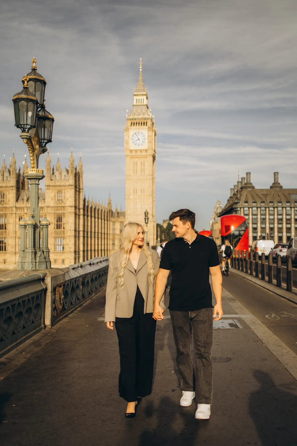 Couple walking hand in hand on Westminster Bridge towards the camera, Big Ben behind