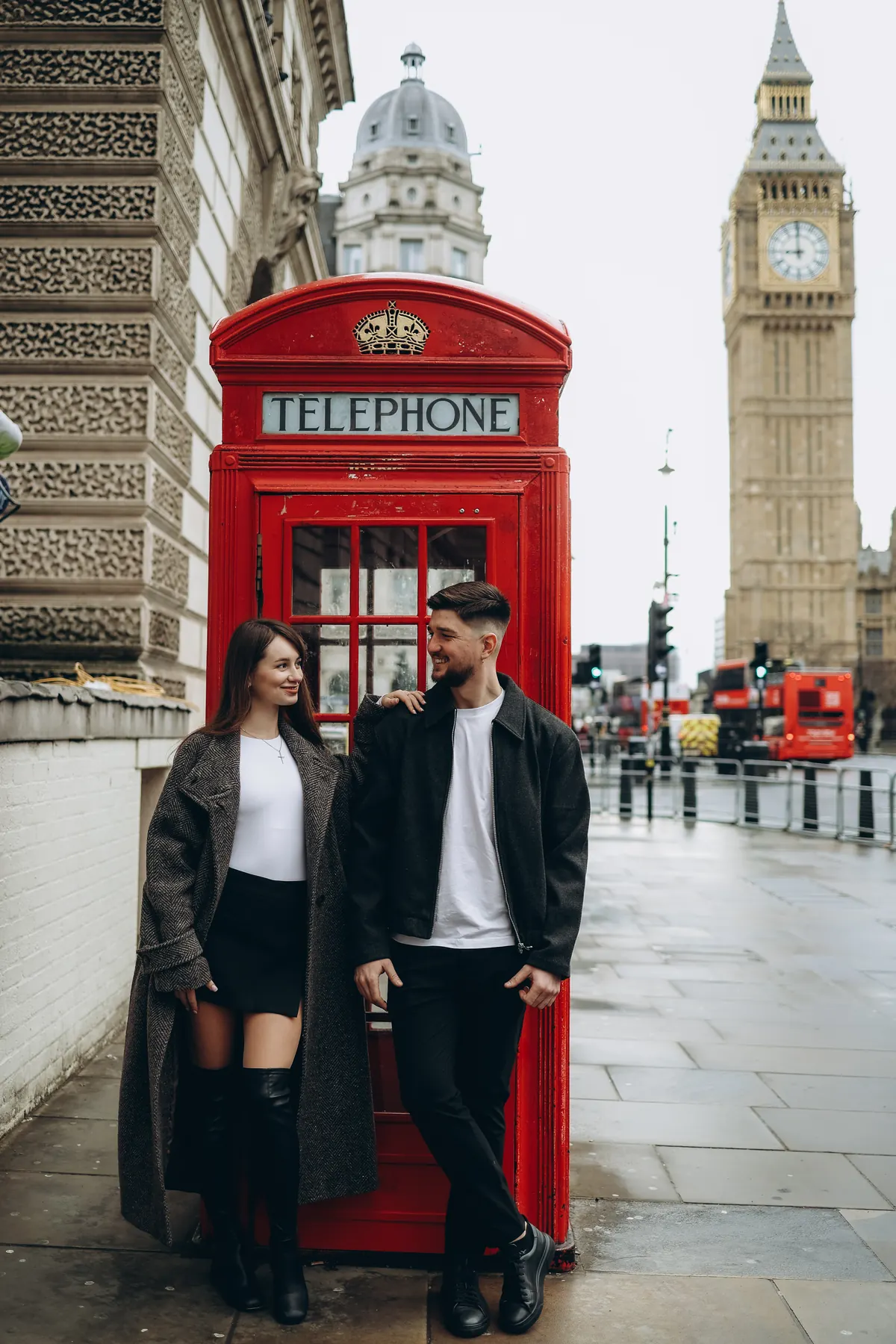 Couple leaning on the red phone box near Parliament Square with Big Ben behind
