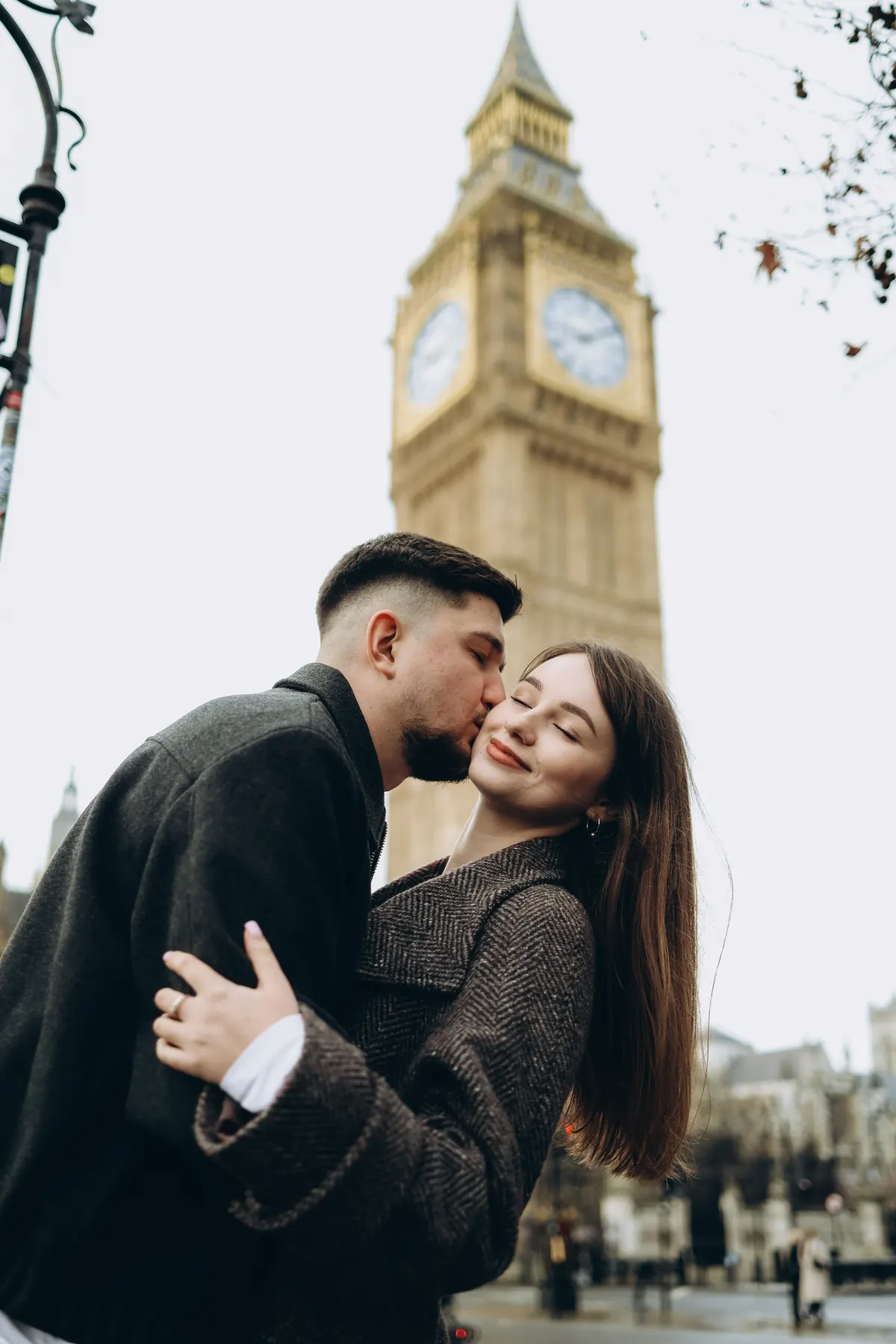 Man kissing his partner on the cheek below the Big Ben clock tower