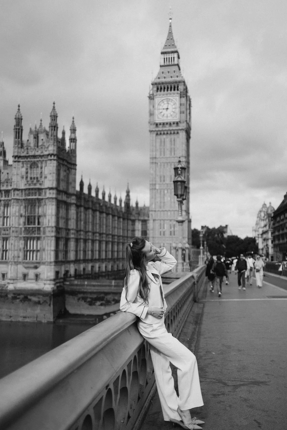 Black and white photo of a woman in a suit on Westminster Bridge below Big Ben
