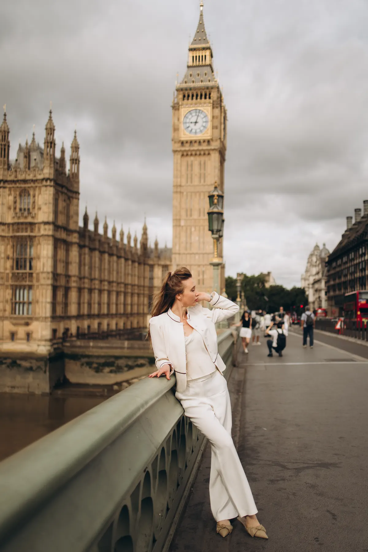 Woman in a white suit leaning on Westminster Bridge with Big Ben behind