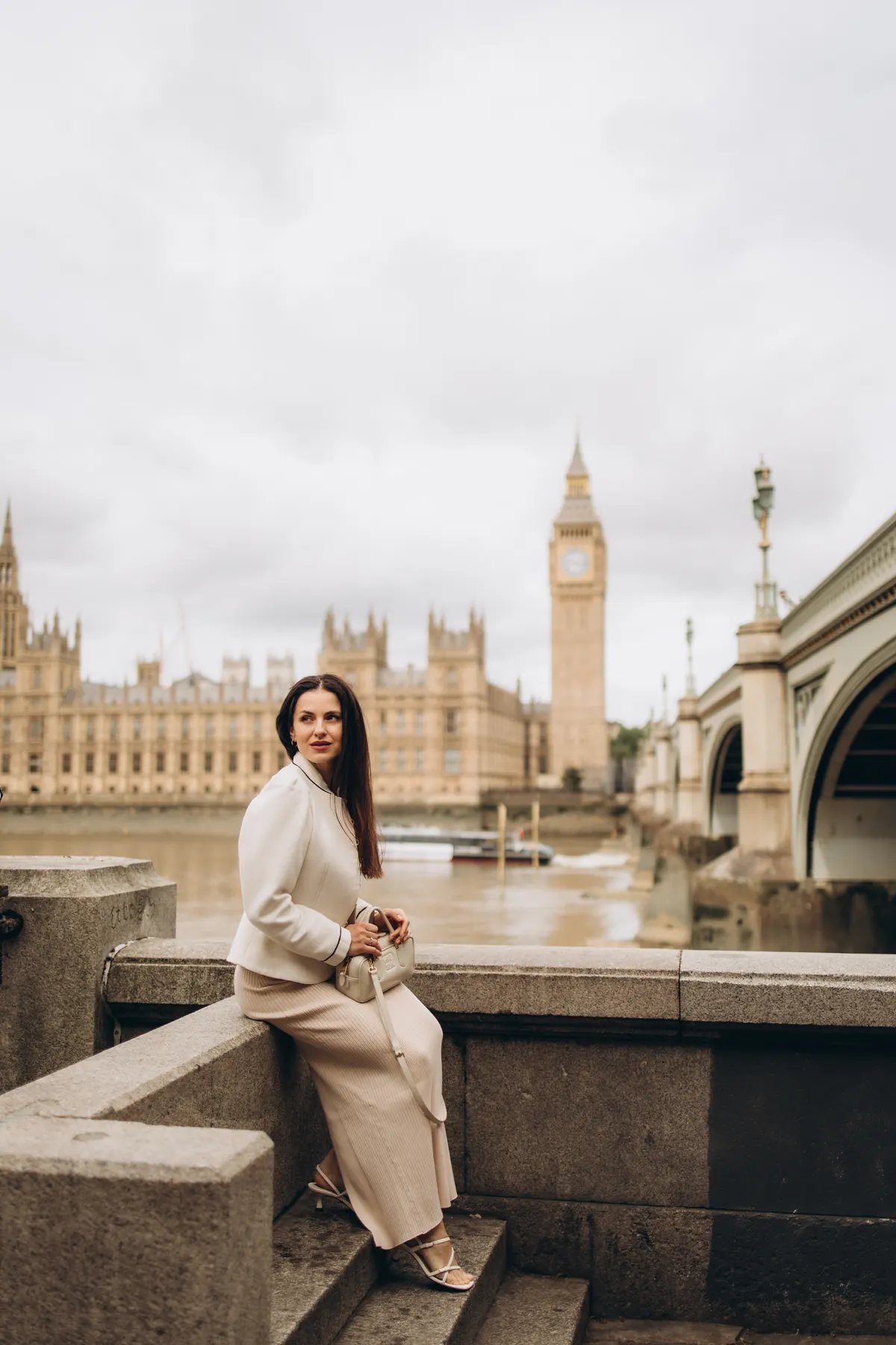 Woman sitting on the steps by the Thames with Big Ben across the river