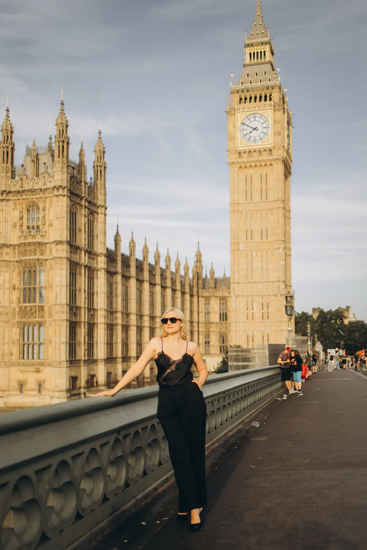 Woman in sunglasses leaning on Westminster Bridge below Big Ben