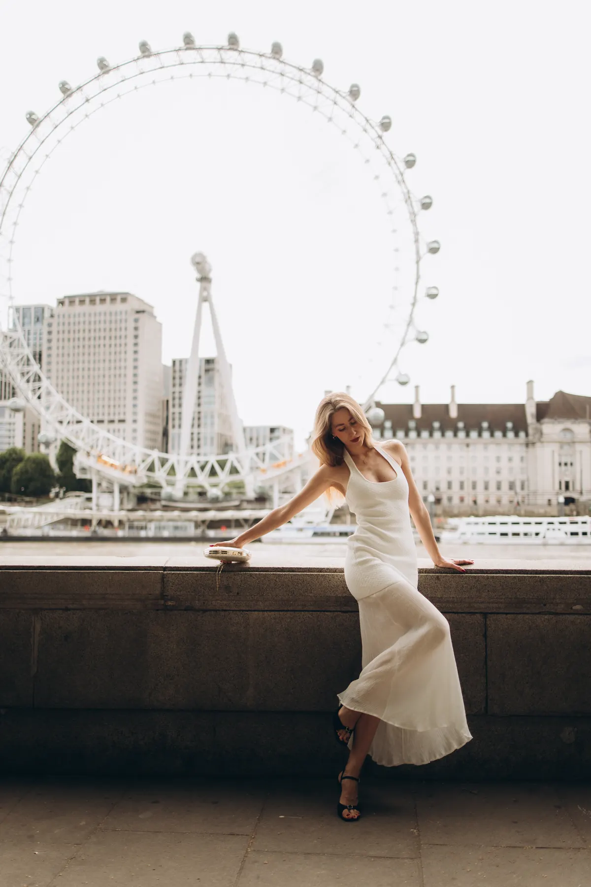 Woman in a white dress on the Thames wall with the London Eye behind