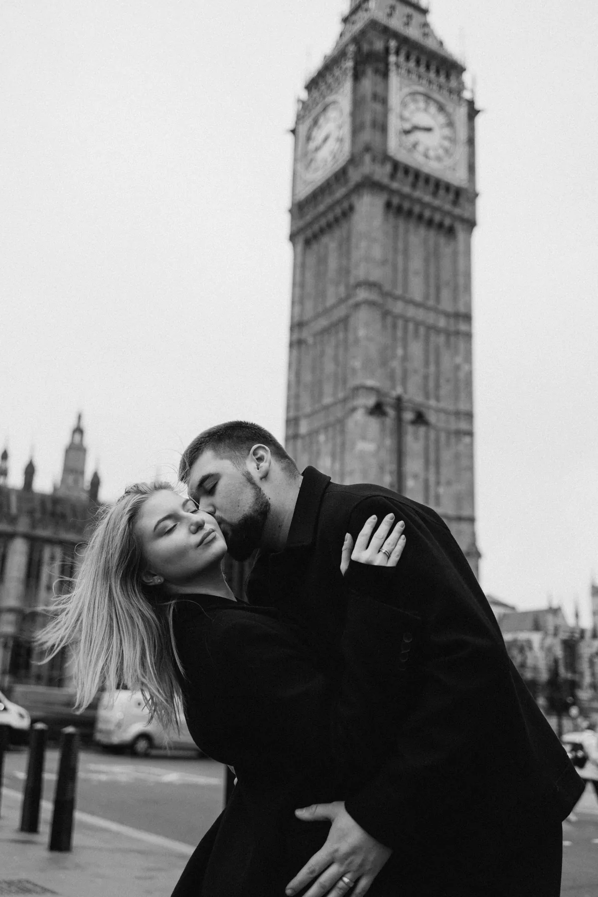 Black and white close-up of a dip kiss with Big Ben behind and hair flying in the wind
