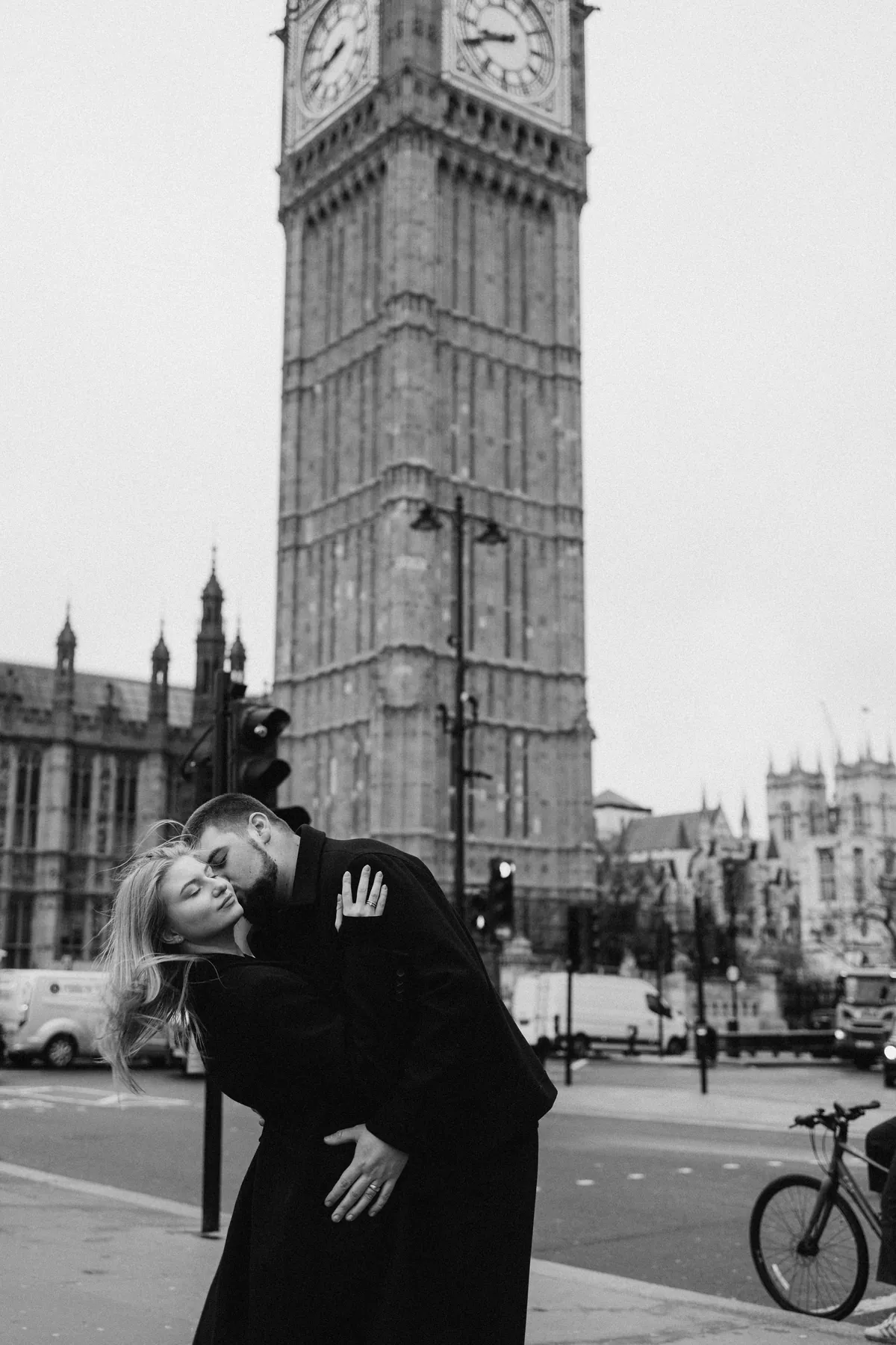 Black and white photo of a man dipping his partner for a kiss in front of Big Ben