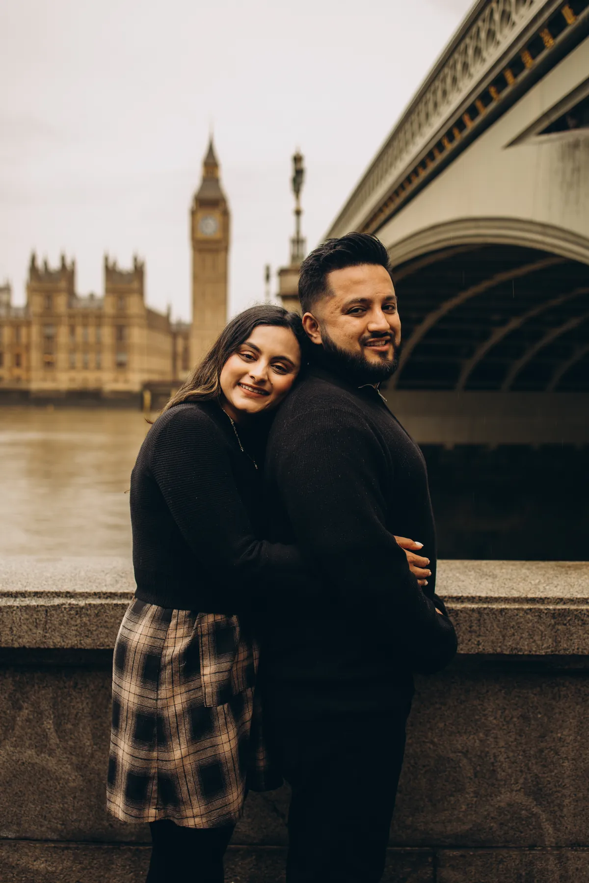 Woman hugging her partner from behind on the South Bank, Big Ben and Westminster Bridge behind