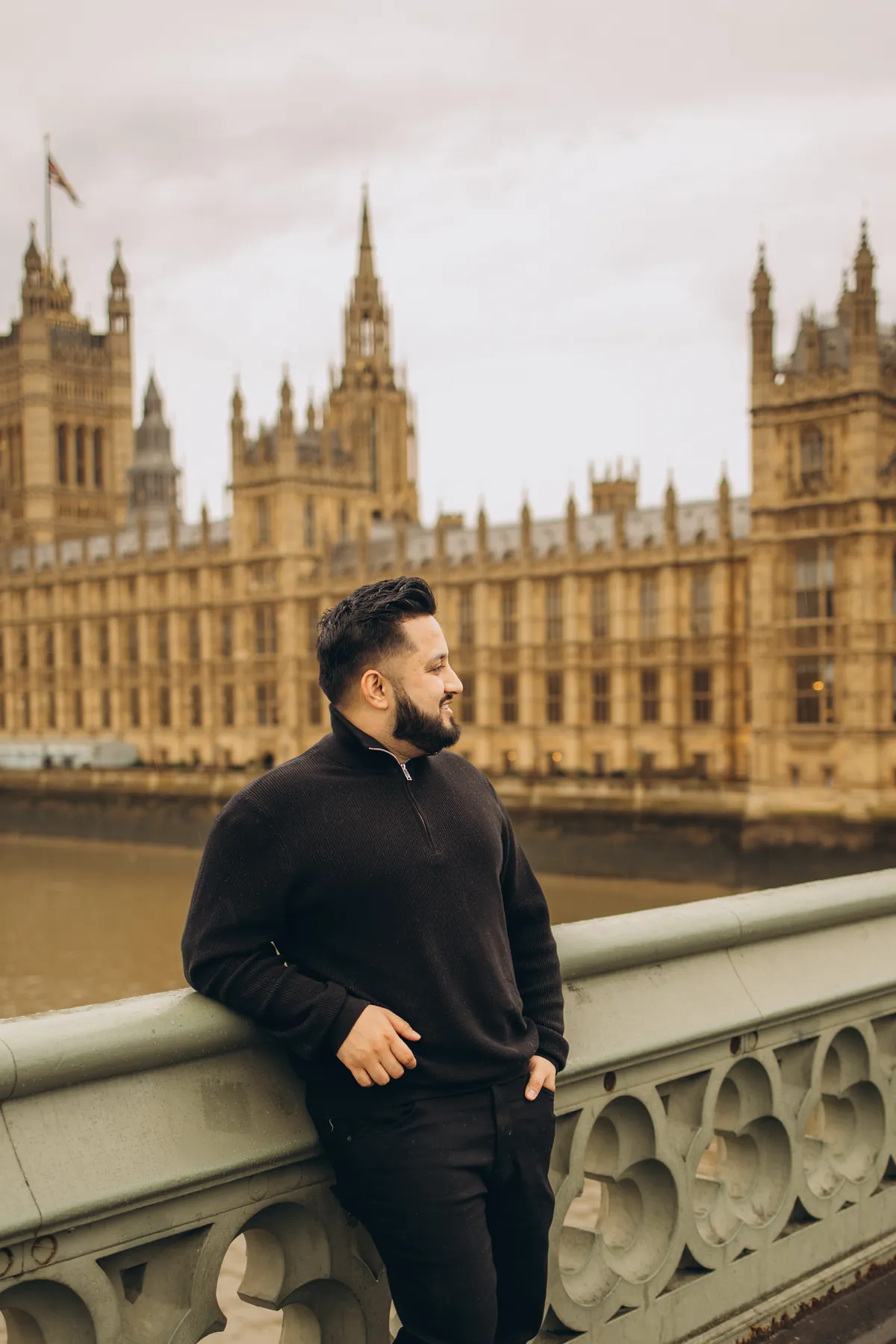 Man leaning on the Westminster Bridge railing, looking towards the Houses of Parliament